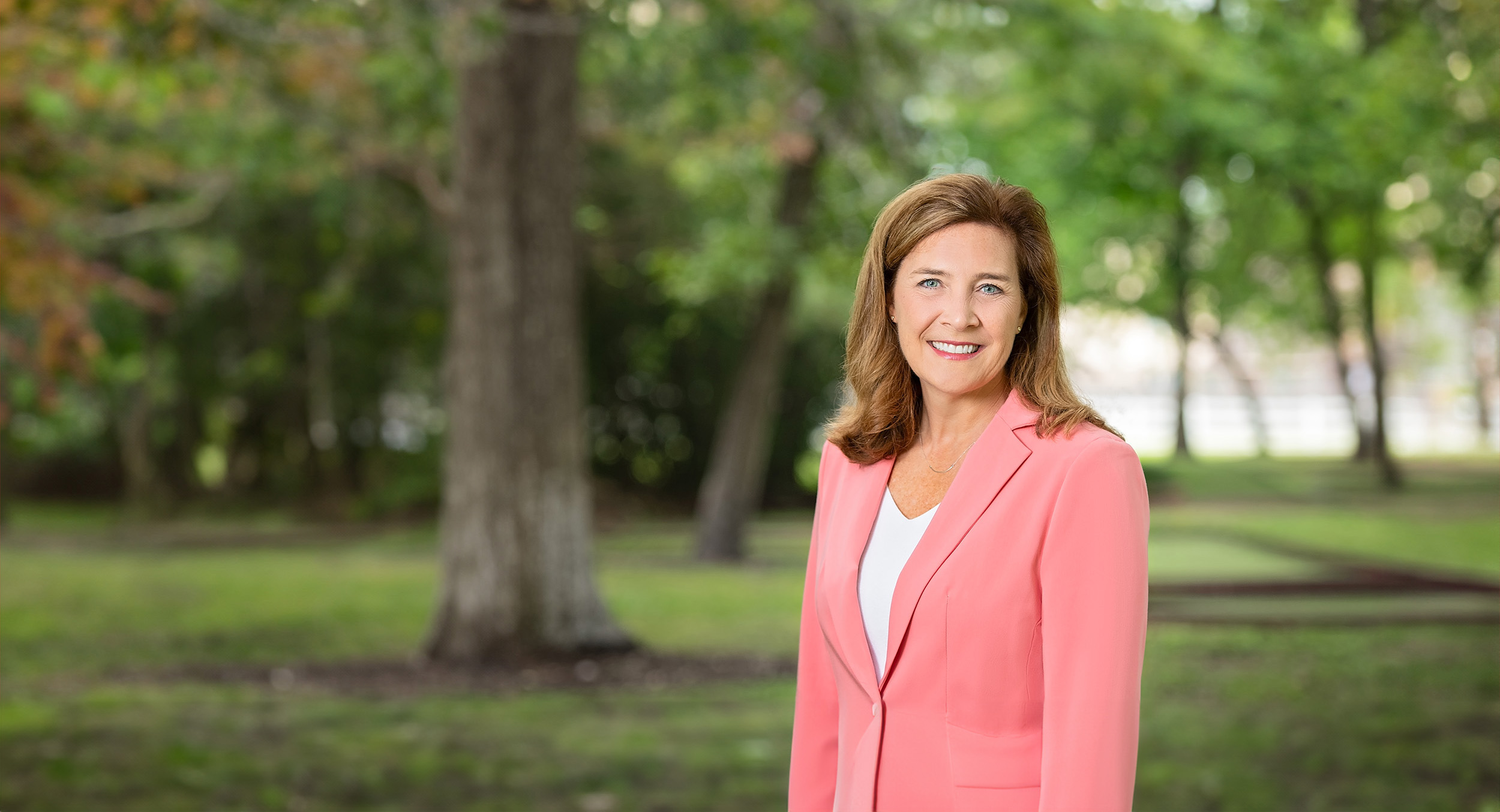 Stephanie Cox, founder of blue sky ambition, posing in pink jacket in the park